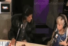 a man and a woman are sitting at a table in front of a microphone with the words unicorn owns your soul on the screen