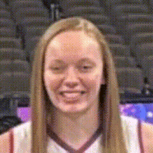 a woman in a basketball uniform is smiling in front of a stadium .