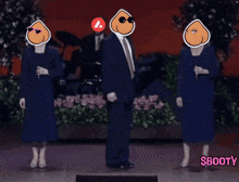 a man in a suit and tie stands in front of two women in blue dresses and a sign that says booty
