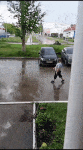 a person walking on a wet road with a car in the background
