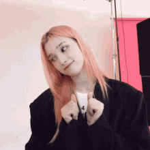 a woman with pink hair is wearing a black jacket and a necklace with the number 4 on it