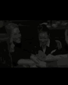a black and white photo of a group of people sitting around a table .