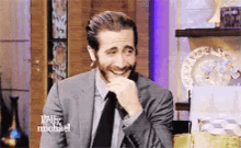 a man in a suit and tie is smiling and covering his mouth