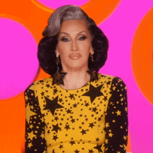 a woman is wearing a yellow top with black stars on it