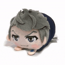 a stuffed animal with gray hair and blue eyes is laying on its side