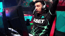 a man wearing headphones and a shirt that says xbet sitting in front of a computer