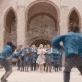 a group of people are standing in front of a building and dancing .