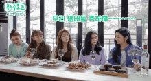 a group of women sitting at a table with plates of food and wine glasses