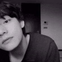 a black and white photo of a young man 's face in a room .