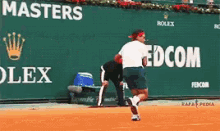 a tennis player in front of a green wall that says masters rolex