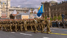 a group of soldiers marching down a street with a blue flag in the background