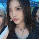 a woman wearing a necklace with a cross on it looks at the camera