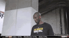 a man wearing a los angeles basketball shirt stands in a room