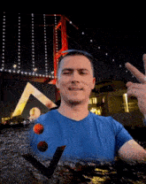 a man in a blue shirt stands in front of a red bridge