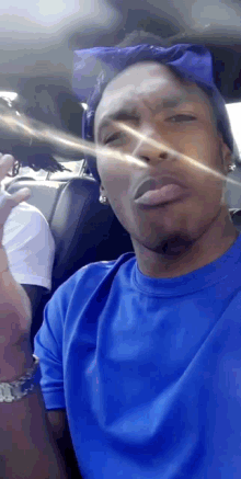 a man wearing a blue shirt and a blue bandana is making a funny face