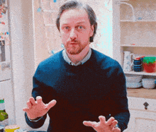 a man in a blue sweater is standing in a kitchen