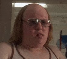 a bald woman wearing glasses is making a funny face .