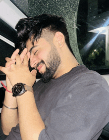 a man with a beard and a watch on his wrist looks down