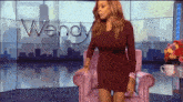a woman in a red dress stands in front of a screen that says wendy on it