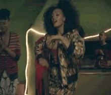 a woman with curly hair is dancing in a room with a green wall