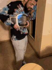 a man in a tie dye shirt is holding a trophy that says champions