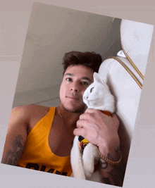 a man in a yellow tank top is holding a cat