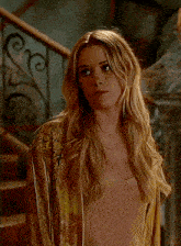 a woman with long blonde hair is wearing a yellow jacket