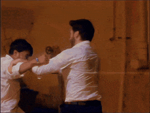 a man in a white shirt is holding another man 's arm