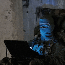 a soldier wearing a mask is using a laptop computer .