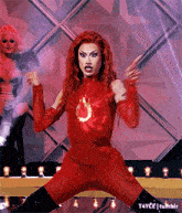 a drag queen is wearing a red outfit and black boots .