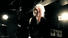 a woman with pink hair stands in front of a sign that says no smoking on it