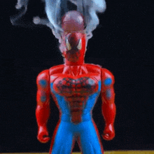 a toy spiderman is standing in front of a black background .