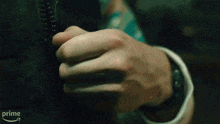 a close up of a person 's hand opening a zipper with an amazon prime arrow in the background