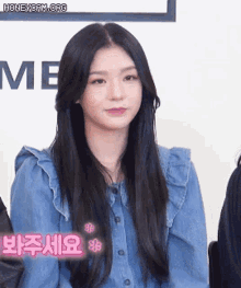 a woman with long black hair is wearing a blue denim shirt and a ruffled collar .