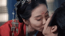 a woman with a red flower on her forehead kissing a man