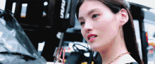 a close up of a woman wearing hoop earrings and a gold chain around her neck