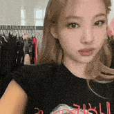 a woman is taking a selfie in front of a row of clothes .
