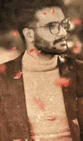 a man wearing glasses and a sweater is surrounded by petals