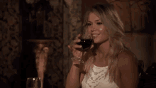 a woman is sitting at a table drinking a glass of wine .