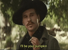 a man with a hat and mustache is smoking a cigarette and says `` i 'll be your pumpkin '' .