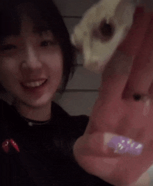 a woman holding a lizard in her hand with a red heart on her shirt