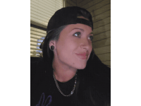 a woman wearing a baseball cap and a necklace with the letter m on her shirt