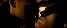 a close up of a man and woman kissing in the dark .