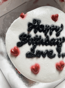 a birthday cake with black frosting and red hearts that says happy birthday love