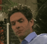 a man in a blue shirt is making a funny face in front of a sign that says caffe macchiato