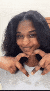 a woman makes a heart shape with her hands