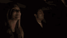 a woman and a man are sitting in a car at night .