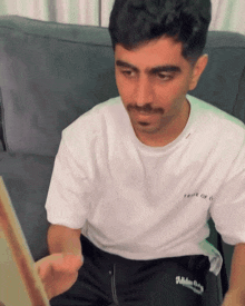 a man sitting on a couch wearing a white t-shirt that says true of 6