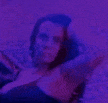 a woman is dancing in a dark room with purple lights .