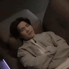 a man is laying on a couch with his arms crossed and making a face .